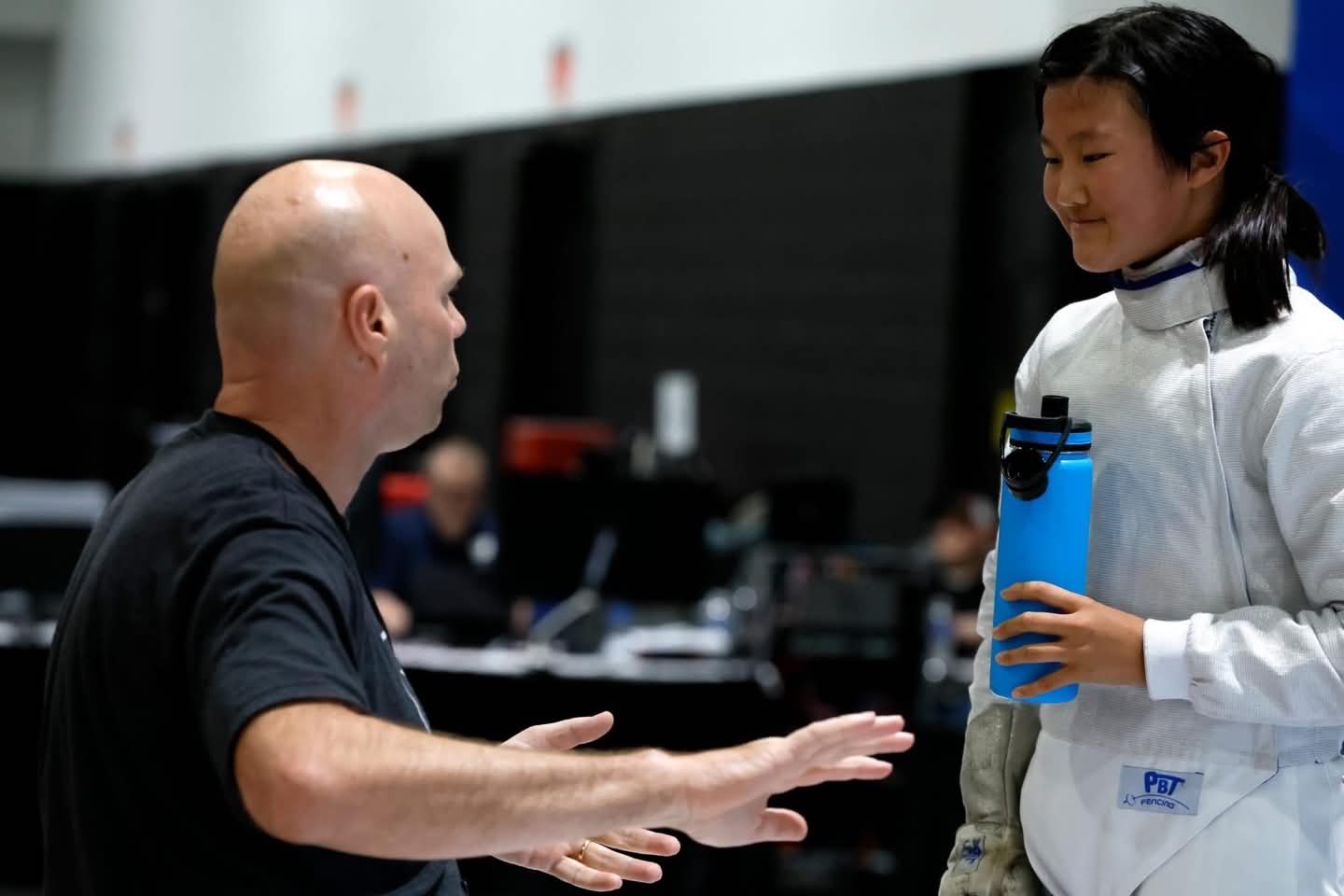 Meester Paul Corteyn geeft aanwijzingen aan een jonge schermster tijdens een wedstrijd in de Verenigde Staten